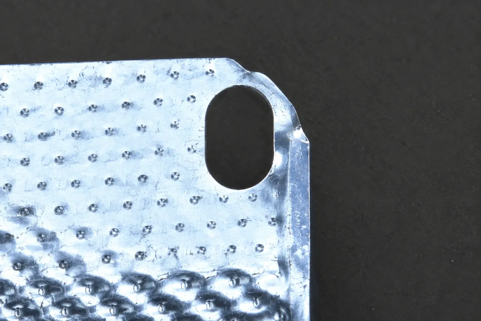 Restored inspection detail showing a damaged edge on a stamped metal hole